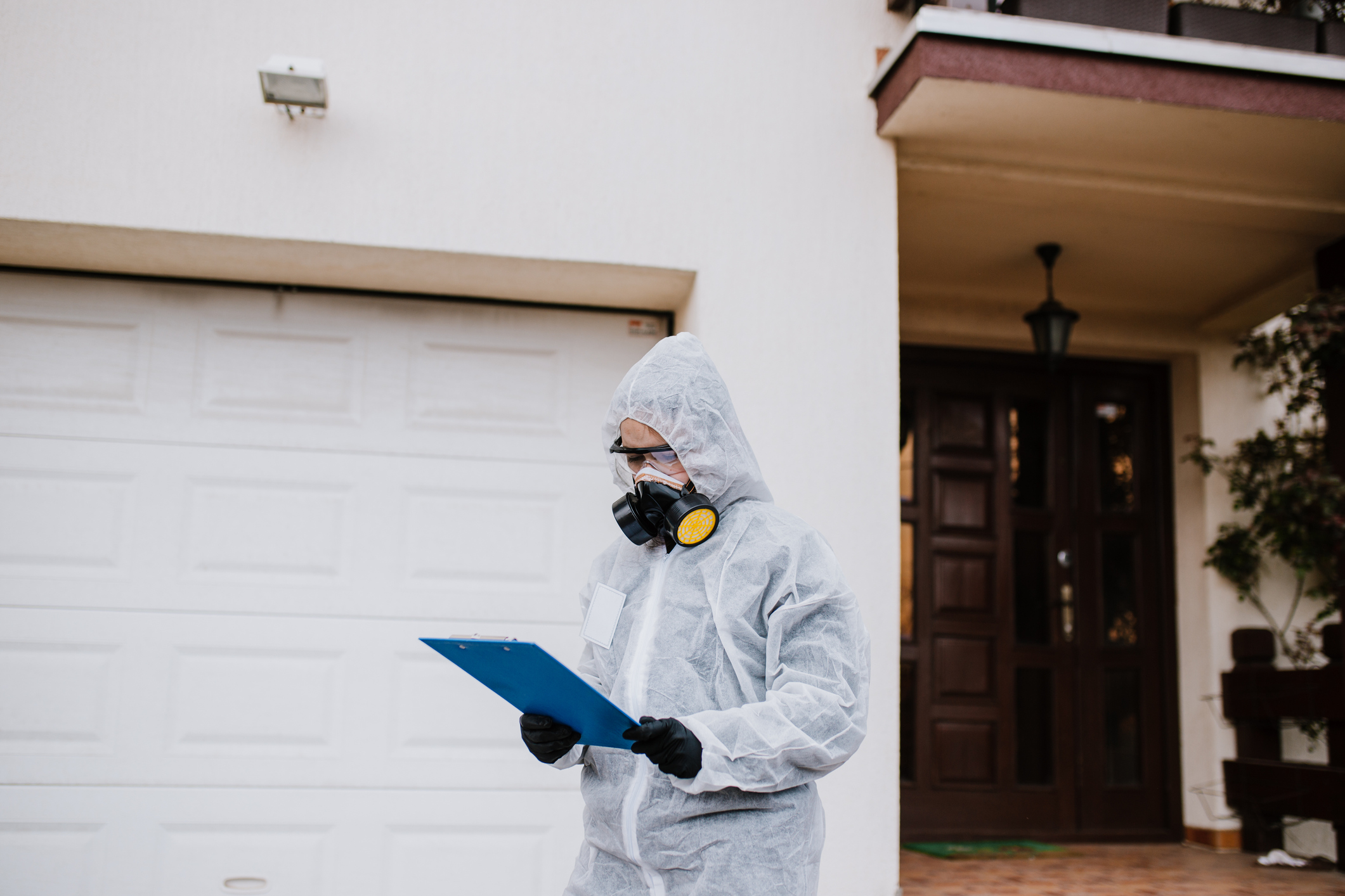 Professional worker in protective workwear reading checklist about house disinfection plan.